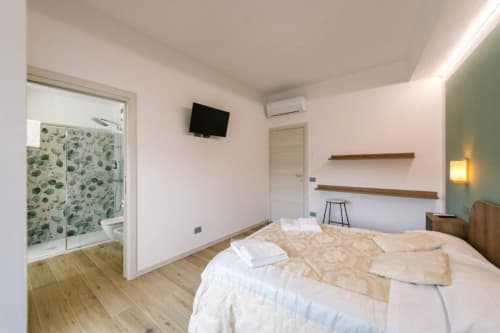 Camera luminosa con pavimenti in legno, doccia ensuite, TV, scaffalature in legno e comfort moderni a Camera Olivo B&B a Verona