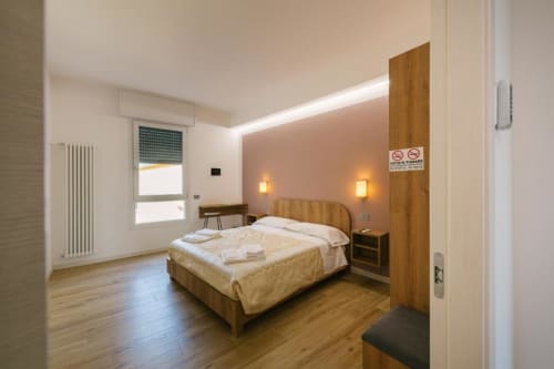 Luminosa camera moderna con letto in legno, applique murali, scrivania e vista sulla città presso Provincia di Verona B&B