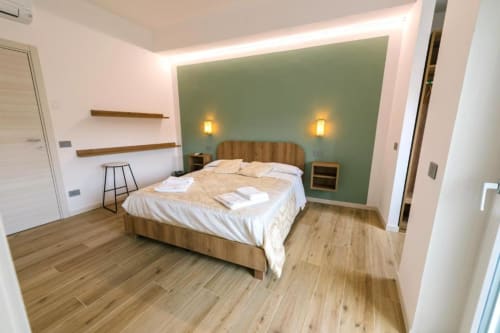 Camera moderna in Provincia di Verona con letto matrimoniale, parete verde, pavimenti in legno e arredi contemporanei