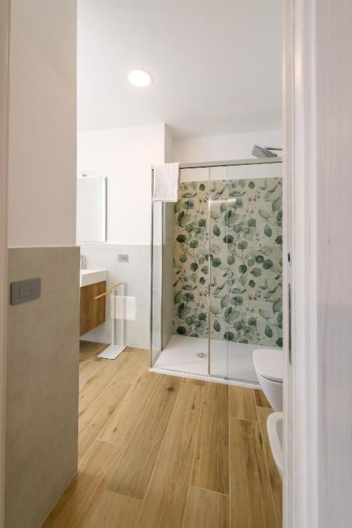 Bagno moderno nella camera Olivo presso il B&B Provincia di Verona con doccia walk-in, pavimenti in legno e piastrelle botaniche
