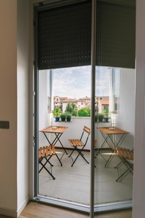 Porte in vetro si aprono sulla terrazza con arredamento in legno con vista sui tetti di Verona presso Camera Olivo B&B