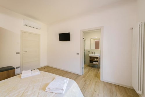 Camera matrimoniale moderna a Verona con pavimento in legno, bagno ensuite, TV e aria condizionata