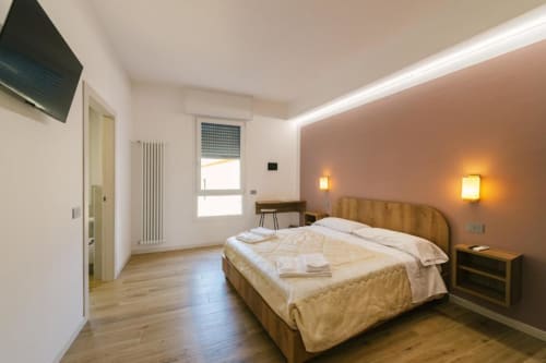 Spazioso camera matrimoniale in B&B a Verona con letto in legno, parete in tono caldo, dotata di comfort moderni e vista sulla città