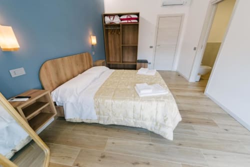 Camera doppia standard a Provincia di Verona B&B con letto, armadio in legno, parete accent blu e ingresso al bagno privato.