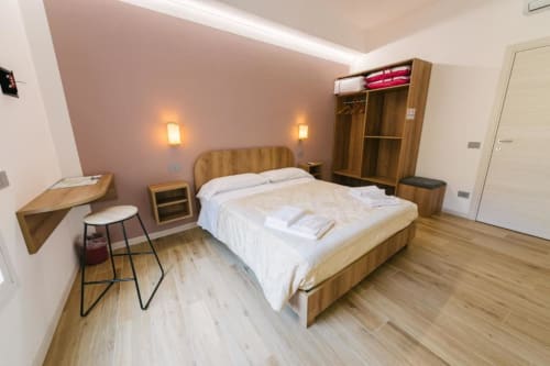 Moderna camera matrimoniale a Provincia di Verona B&B con mobili in legno, biancheria bianca, illuminazione soffusa e vista sulla città