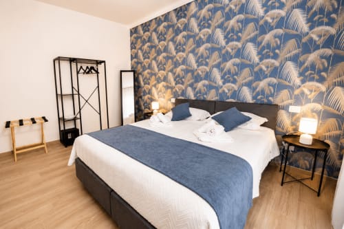 Stanza Blu Palm presso Le Rooms B&B a San Benedetto del Tronto, con carta da parati a motivi di palme blu, letto scuro e vista sulla città
