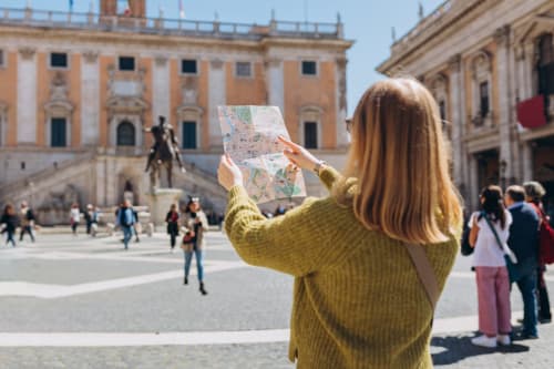 Turista con mappa nella piazza storica di Roma vicino alla lussuosa Trevi House, circondata dall'architettura rinascimentale
