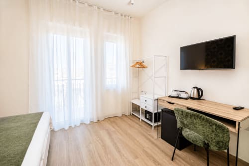 Camera moderna presso Le Rooms a San Benedetto del Tronto con scrivania in legno, TV a schermo piatto, balcone con vista giardino e