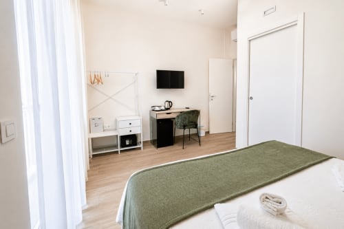 Camera moderna a Le Rooms B&B a San Benedetto del Tronto con letto, scrivania, TV e vista sul giardino