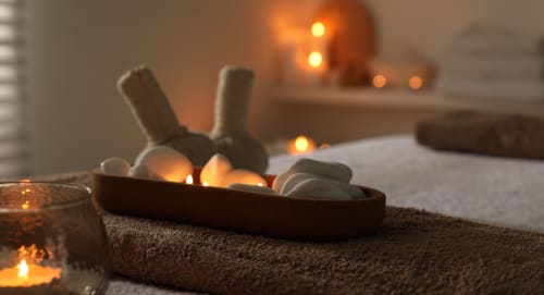 Allestimento spa rilassante presso il Luxury Trevi House Rome con pietre, candele e asciugamani che creano un'atmosfera di benessere sereno