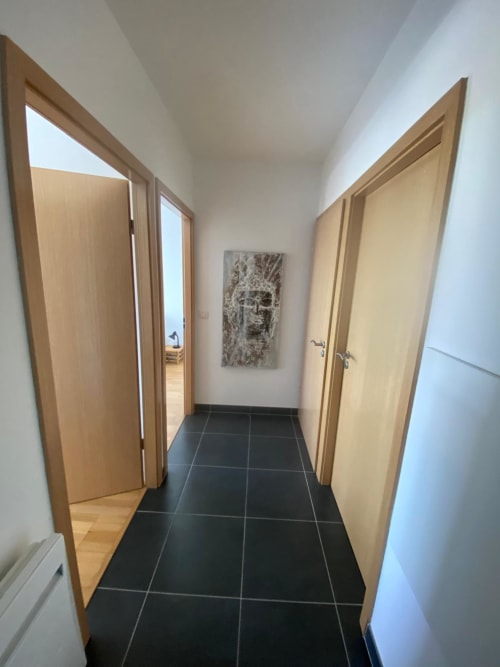 Couloir moderne avec portes en bois, carrelage foncé et décoration murale artistique à l'appartement La Parenthèse, La Rochelle