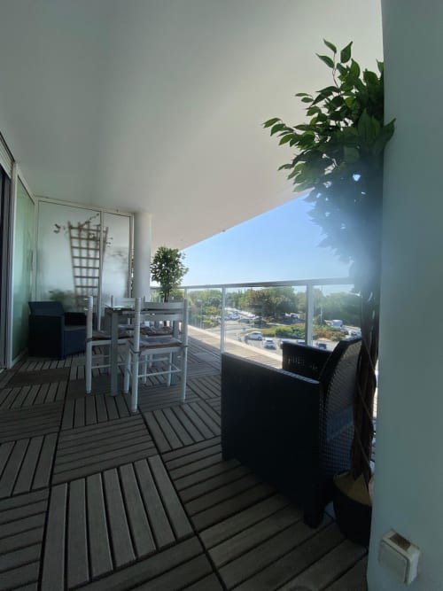 Spacieux balcon de l'appartement La Parenthèse à La Rochelle avec coin repas, vue sur la ville et plantes verdoyantes