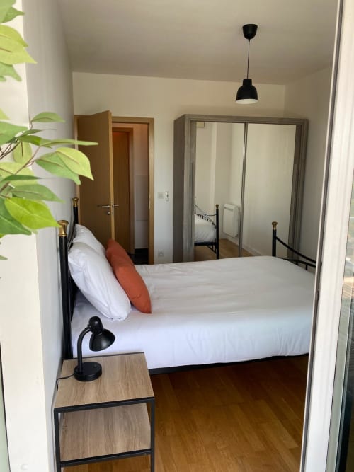 Chambre moderne de l'appartement La Parenthèse à La Rochelle avec lit, armoire miroir et décoration contemporaine