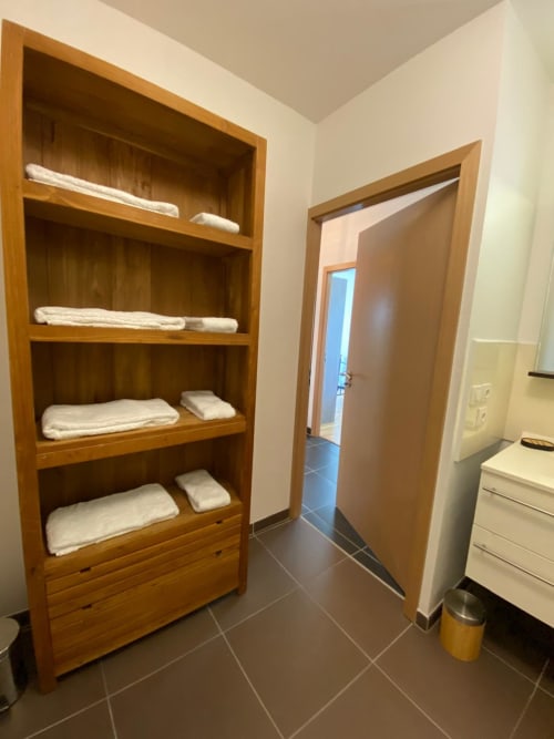 Armoire en bois avec serviettes pliées dans la salle de bain de l'appartement de La Rochelle