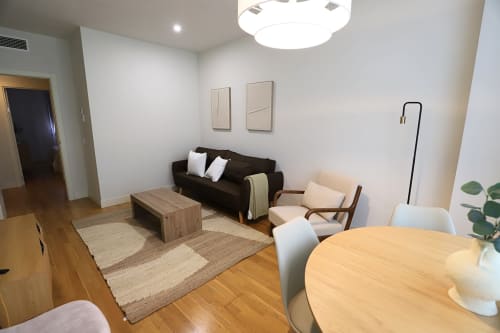 Moderno apartamento en Madrid Río con sala abierta, sofá negro, muebles de madera y diseño contemporáneo
