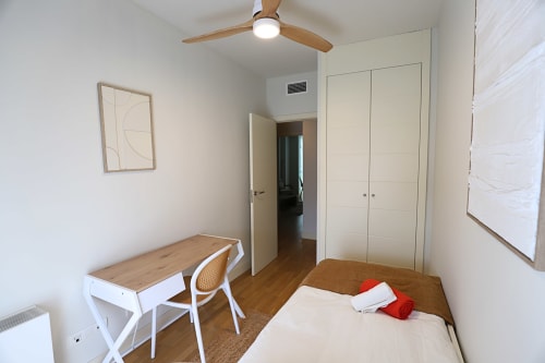 Dormitorio moderno en Apartamento diseño Madrid Río con escritorio, cama, ventilador de techo y armario empotrado