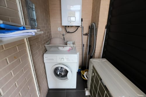 Lavadero con lavadora blanca, lavamanos, calentador de agua y almacenamiento en apartamento Madrid Río, Madrid