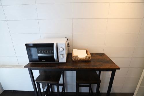 Cocina americana del apartamento Madrid Río con microondas, electrodomésticos blancos y cesta tejida sobre encimera de madera oscura