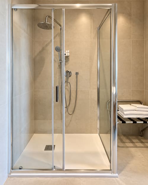 Doccia moderna con pareti in vetro e soffione a cascata nella Suite Giardino Segreto di Domus Fysi, Palermo