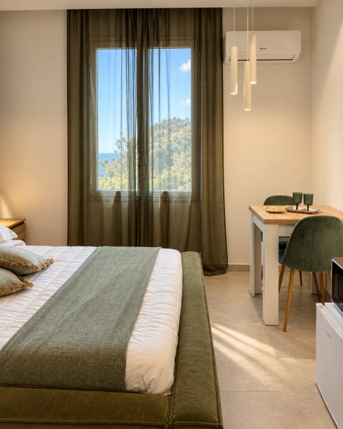 Luminosa suite con camera da letto a Domus Fysi a Palermo, vista mare dalle ampie finestre, arredamento moderno e verde oliva