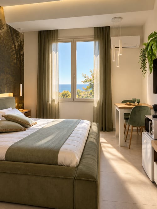 Luminosa suite a Domus Fysi Palermo con vista mare, tonalità olivastre, letto moderno, scrivania e balcone sul Mediterraneo