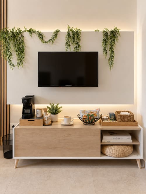 Parete TV moderna con piante sospese, consolle in legno e macchina da caffè nella suite Domus Fysi a Palermo