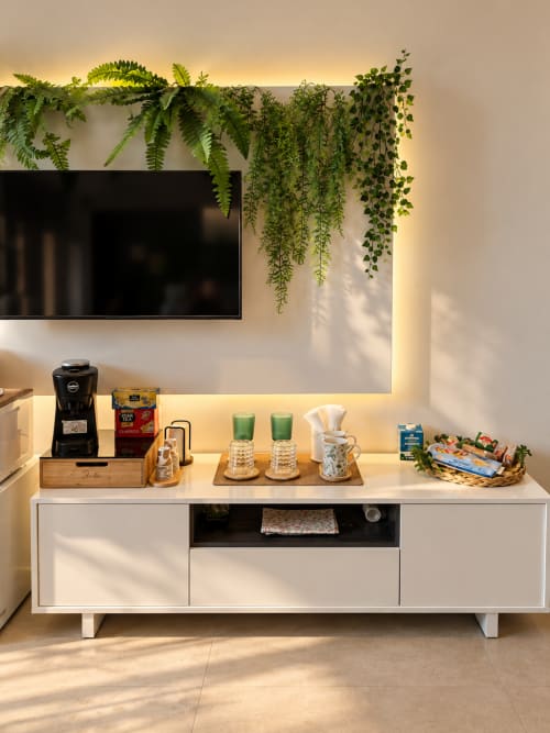 Suite moderna a Domus Fysi Palermo con TV a parete, mobile bianco, piante verdi sospese e illuminazione ambientale calda