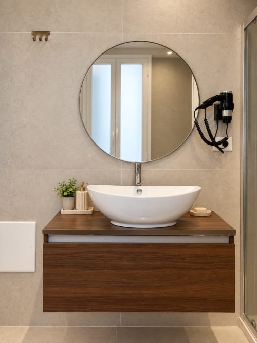 Vanity moderna del bagno con lavabo ovale bianco e specchio rotondo nella suite Domus Fysi di Palermo, Italia
