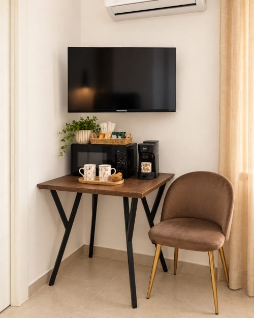 Spazio di lavoro Suite Terra Eden presso Domus Fysi Palermo con TV, scrivania, poltrona marrone, macchina da caffè e piante