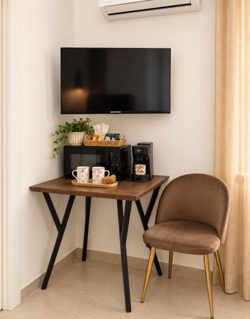 Scrivania compatta presso Domus Fysi Palermo con zona caffè, sedia marrone e TV a parete in ambiente minimalista.