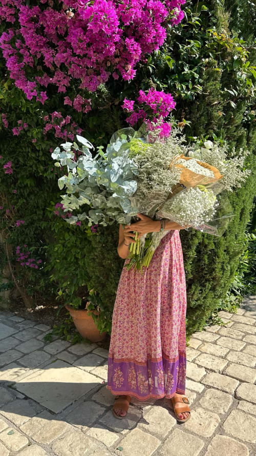 Personne tenant un bouquet éclatant à l'Hôtel Les Lauriers à Saint-Tropez, entourée de fleurs de bougainvillée magenta