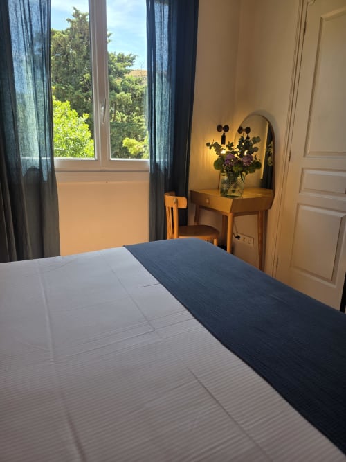 Chambre lumineuse à l'Hôtel Les Lauriers à Saint-Tropez avec vue sur le jardin, coiffeuse en bois avec fleurs et touches de bleu