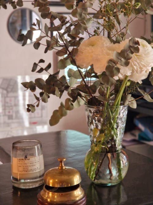 Élégant arrangement floral à l'Hôtel Les Lauriers à Saint-Tropez avec roses pêche, eucalyptus et clochette de service en laiton
