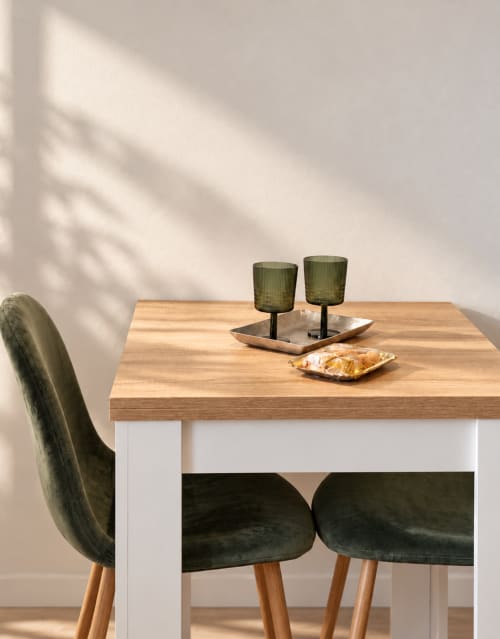 Ambiente minimalista a Domus Fysi Palermo con tavolo in legno, sedie in velluto verde e arredamento moderno