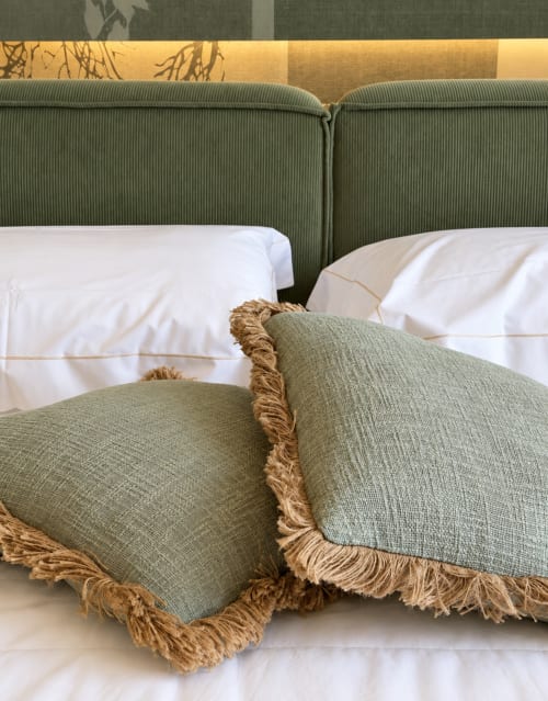 Lussuoso letto presso Domus Fysi Palermo con cuscini verdi, bordi dorati e biancheria bianca in questa elegante camera da letto B&B.