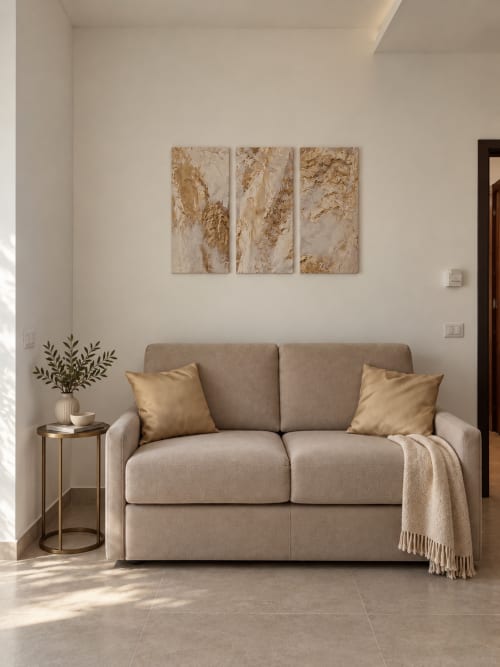 Elegante living room della suite Domus Fysi con divano beige, cuscini dorati e arte astratta murale a Palermo