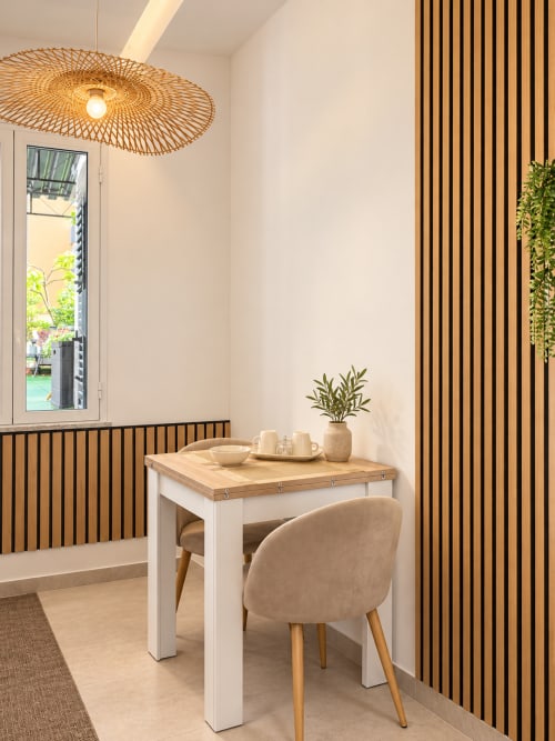 Angolo pranzo moderno nella Suite Sole e Luce di Domus Fysi a Palermo, con lampada a sospensione intrecciata, tavolo in legno, sedia beige e vista mare
