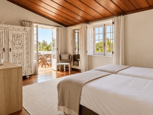 Bright familiar room at Vila Louro with double beds, wooden ceiling, balcony access, and views of green landscape in Santa