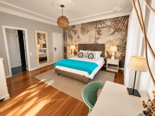 Luxury bedroom at Vila Louro with turquoise bedding, botanical wallpaper, wooden floors, and garden views in Santa Cruz