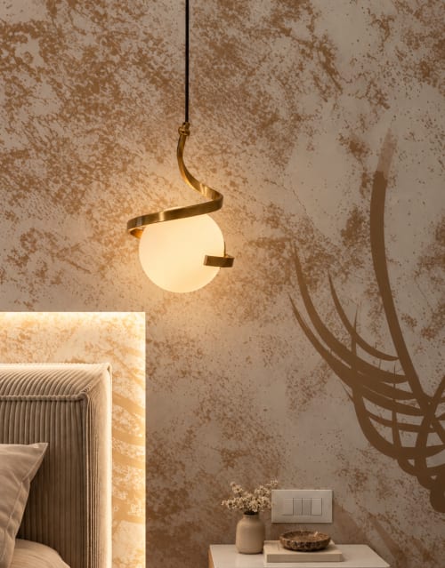 Moderna lampada a sospensione con design a spirale in ottone sopra il comodino dell'hotel boutique Domus Fysi a Palermo