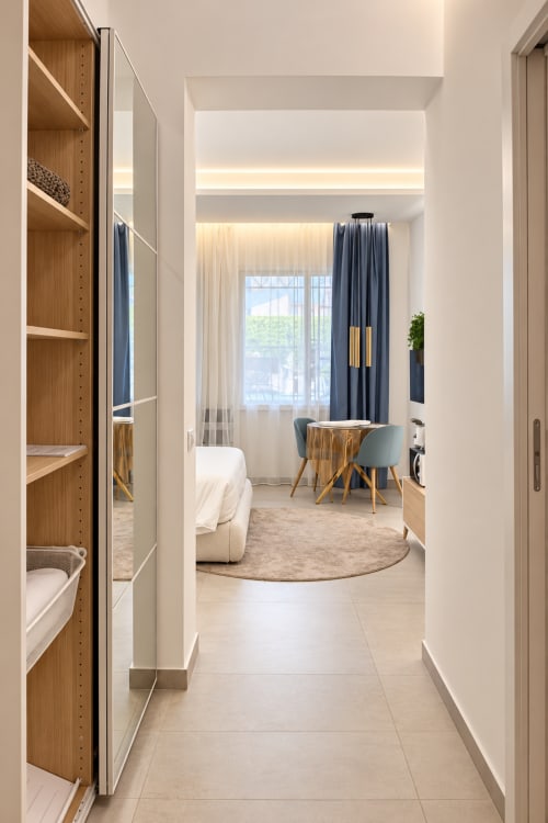 Ingresso della suite moderna a Domus Fysi Palermo con scaffali in legno, vista sulla città, zona pranzo e arredi contemporanei