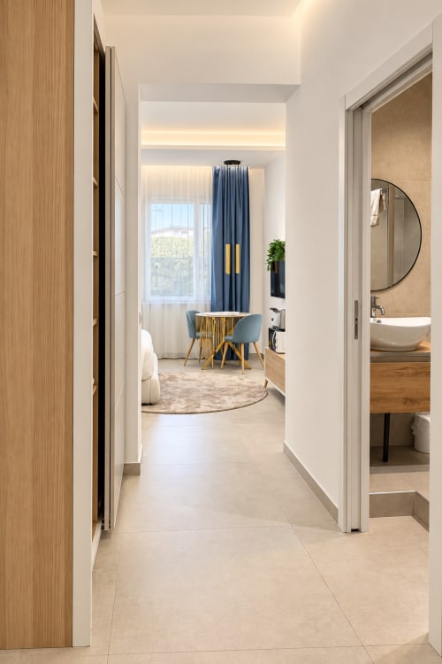 Corridoio moderno della suite Domus Fysi a Palermo, accesso alla camera con tende blu e vista città, bagno con specchio rotondo