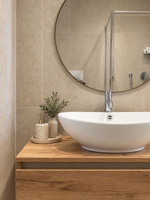 Lavabo moderno in ceramica bianca con specchio rotondo e mobile in legno nella Suite Riflessi Marini di Domus Fysi, Palermo