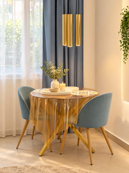 Elegante zona pranzo della suite Palermo con tavolo dorato, sedie grigie, lampade a sospensione e vista sulla città dalle finestre