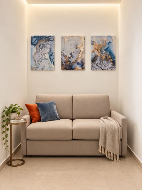 Elegante divano beige con cuscini decorativi nella Suite Riflessi Marini del Domus Fysi Palermo B&B, con dettagli astratti blu e oro
