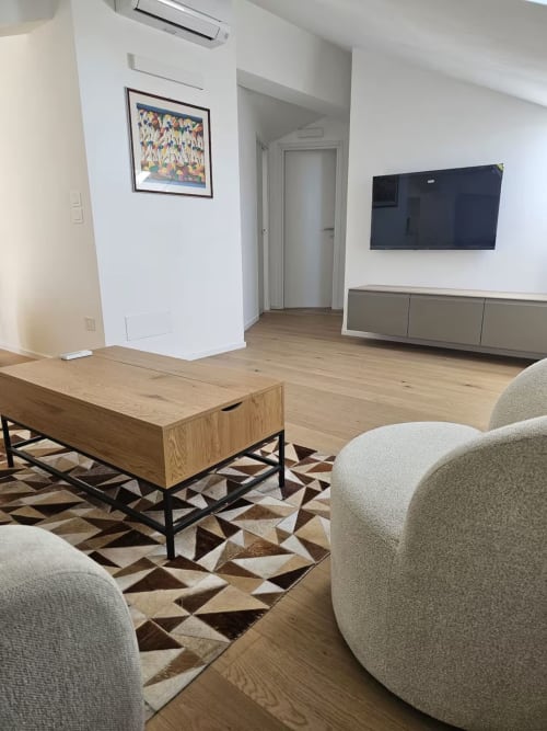 Moderno salotto della Pescara INN con poltrone beige, tavolino in legno, TV schermo piatto e tappeto a motivi geometrici