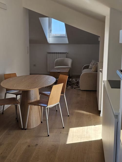 Moderna zona pranzo dell'appartamento Pescara INN con tavolo rotondo in legno, sedie e comodi posti a sedere sotto i lucernari