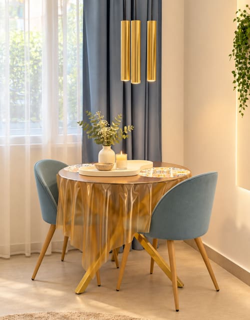 Elegante sala da pranzo di Domus Fysi Palermo con tavolo dorato, sedie grigie, lampade a sospensione e tende grigie.