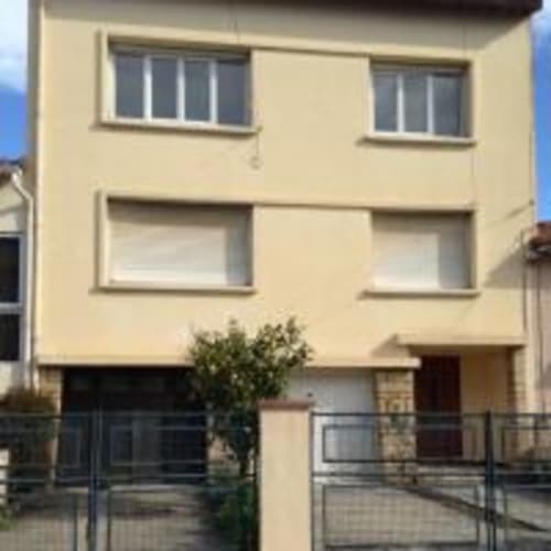 Immeuble d'habitation couleur crème à Perpignan avec fenêtres et rampes métalliques au rez-de-chaussée