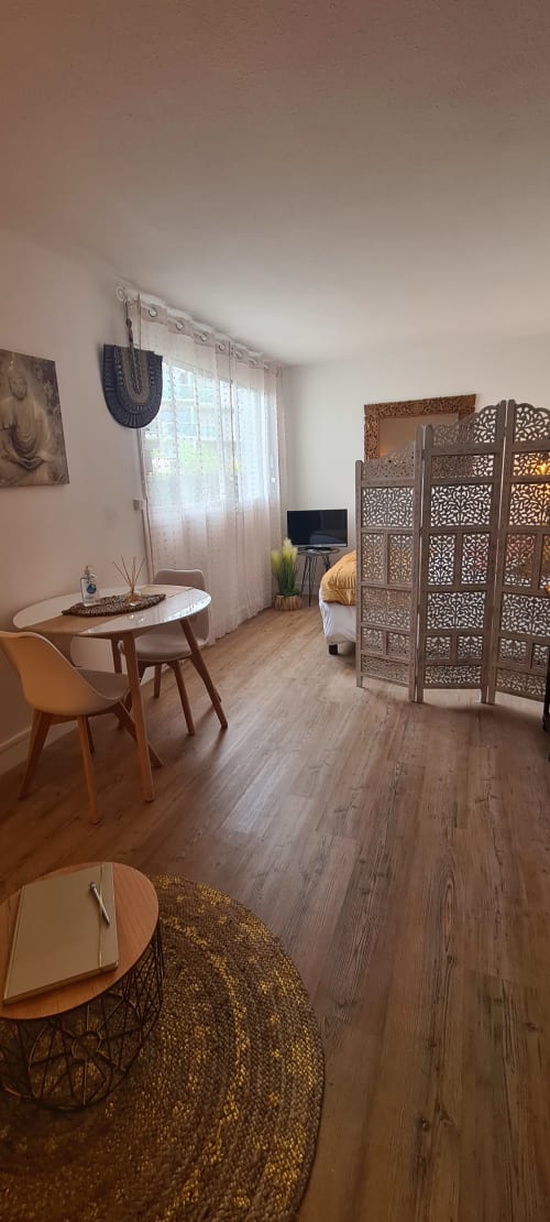 Suite studio aux Suites Du Port, Arcachon - séjour avec mobilier bois, paravent décoratif et vue sur la ville